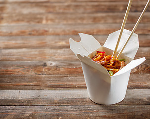 Image showing Noodles with pork and vegetables in take-out box on wooden table