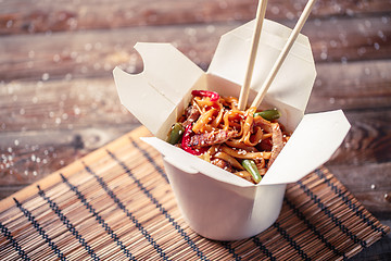 Image showing Noodles with pork and vegetables in take-out box on wooden table