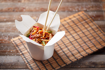 Image showing Noodles with pork and vegetables in take-out box on wooden table