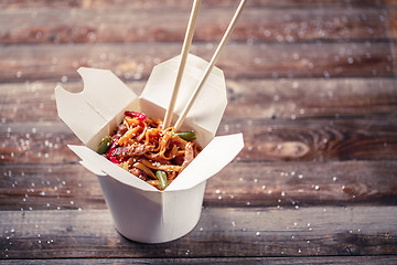 Image showing Noodles with pork and vegetables in take-out box on wooden table