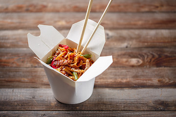 Image showing Noodles with pork and vegetables in take-out box on wooden table