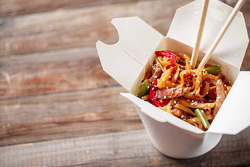 Image showing Noodles with pork and vegetables in take-out box on wooden table