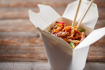 Image showing Noodles with pork and vegetables in take-out box on wooden table