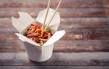 Image showing Noodles with pork and vegetables in take-out box on wooden table