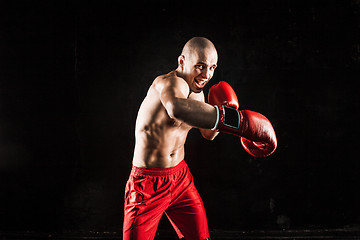 Image showing The young man kickboxing on black