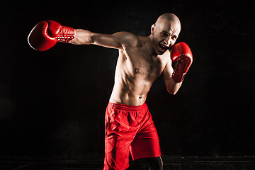 Image showing The young man kickboxing on black