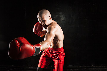 Image showing The young man kickboxing on black