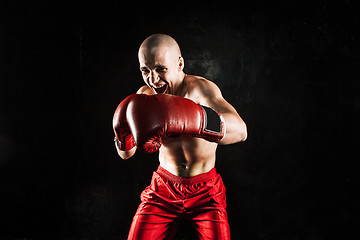 Image showing The young man kickboxing on black