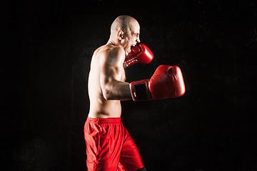 Image showing The young man kickboxing on black