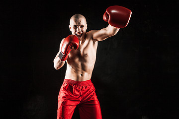 Image showing The young man kickboxing on black