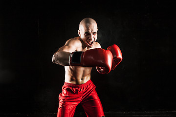 Image showing The young man kickboxing on black