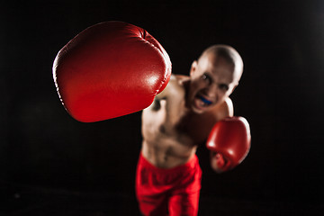 Image showing The young man kickboxing on black  with kapa in mouth