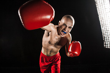 Image showing The young man kickboxing on black  with kapa in mouth