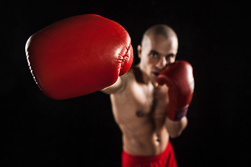 Image showing The young man kickboxing on black  with kapa in mouth