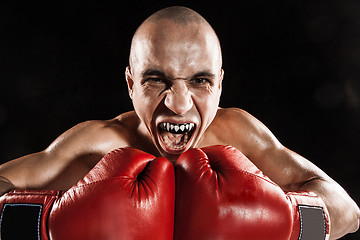 Image showing The young man kickboxing on black  with kapa in mouth