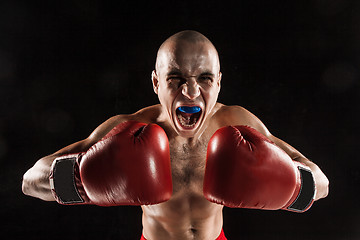 Image showing The young man kickboxing on black  with kapa in mouth