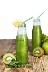 Image showing The bottles with fresh vegetable juices on wooden table