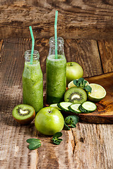 Image showing The bottles with fresh vegetable juices on wooden table