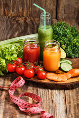 Image showing The bottles with fresh vegetable juices on wooden table