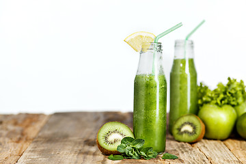 Image showing The bottles with fresh vegetable juices on wooden table