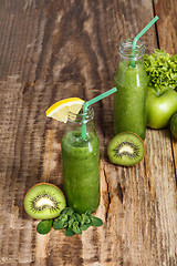 Image showing The bottles with fresh vegetable juices on wooden table