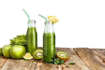 Image showing The bottles with fresh vegetable juices on wooden table