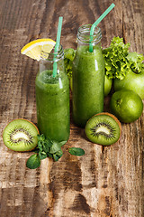 Image showing The bottles with fresh vegetable juices on wooden table