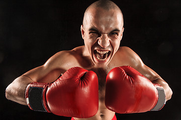 Image showing The young man kickboxing on black  with screaming face