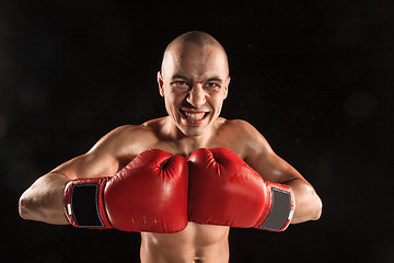 Image showing The young man kickboxing on black  with screaming face