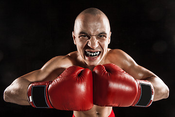 Image showing The young man kickboxing on black  with kapa in mouth