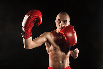 Image showing The young man kickboxing on black