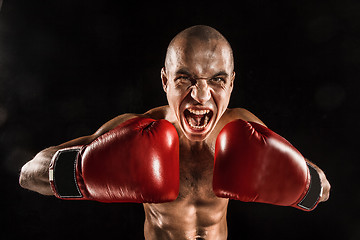 Image showing The young man kickboxing on black  with screaming face