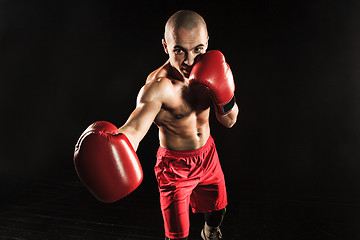 Image showing The young man kickboxing on black