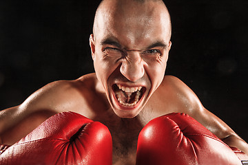 Image showing The young man kickboxing on black  with screaming face