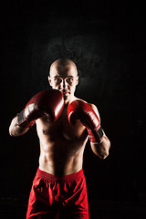 Image showing The young man kickboxing on black