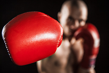 Image showing The young man kickboxing on black