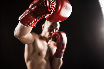 Image showing The young man kickboxing on black