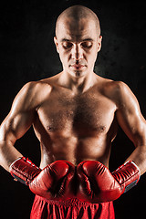 Image showing The young man kickboxing on black