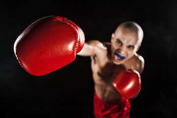 Image showing The young man kickboxing on black  with kapa in mouth