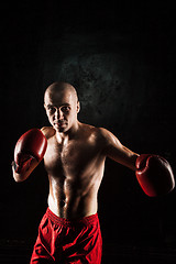 Image showing The young man kickboxing on black