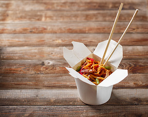 Image showing Noodles with pork and vegetables in take-out box on wooden table