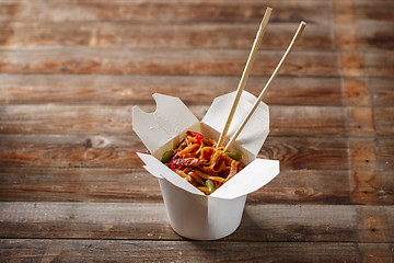 Image showing Noodles with pork and vegetables in take-out box on wooden table