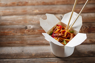 Image showing Noodles with pork and vegetables in take-out box on wooden table