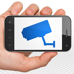 Image showing Protection concept: Hand Holding Smartphone with Cctv Camera on display