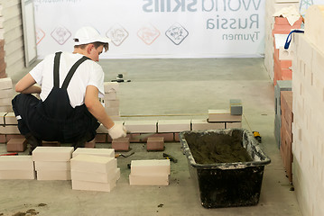 Image showing Young bricklayer performs a task of competition