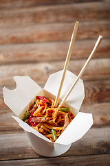 Image showing Noodles with pork and vegetables in take-out box on wooden table