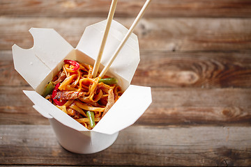 Image showing Noodles with pork and vegetables in take-out box on wooden table