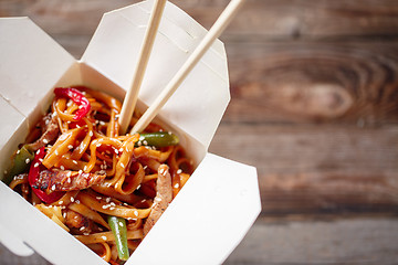 Image showing Noodles with pork and vegetables in take-out box on wooden table