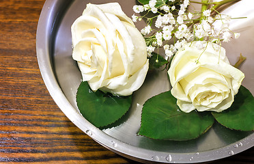 Image showing Beautiful rose on the surface of the vessel with water.