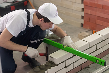 Image showing Young bricklayer performs a task of competition